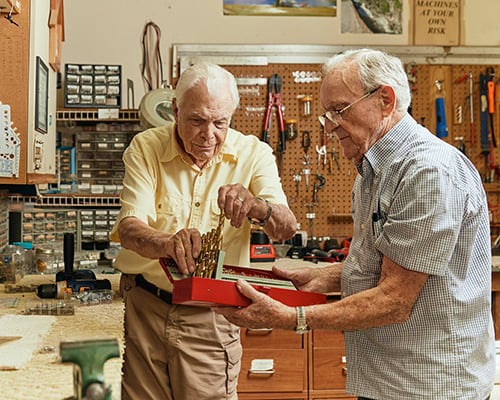 Two elderly men working in a workshop.