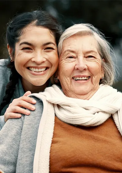 Senior and caregiver smiling together.